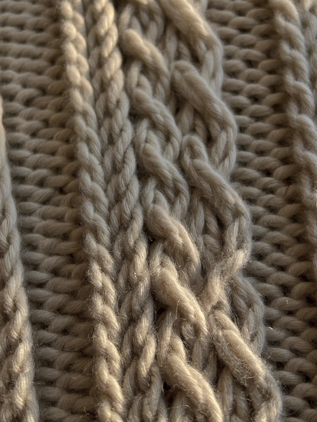 Close-up of hand-knitted cables in oatmeal merino wool
