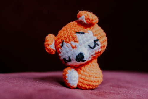 Handmade crochet amigurumi animal on a soft pink surface